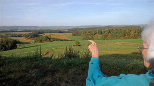 Mirjami deutet von einer Anhöhe in die Landschaft. Hier ist sie, als sie noch besser laufen konnte, viel unterwegs gewesen.