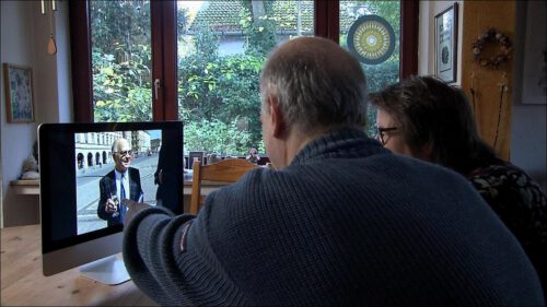 Tim Willy Weber und Silvia Gauß sitzen am Tisch und schauen gemeinsam die erste POINT-Reportage von 1995 auf einem Bildschirm.