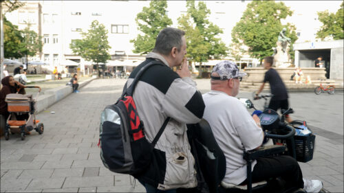 Marco ist blind. Sein Freund Marco geleitet ihn mit dem elektrischen Rollstuhl über den Platz; sie gehören zum Stammpublikum. Marco ist blind. Sein Freund Marco geleitet ihn mit dem elektrischen Rollstuhl über den Platz; sie gehören zum Stammpublikum.